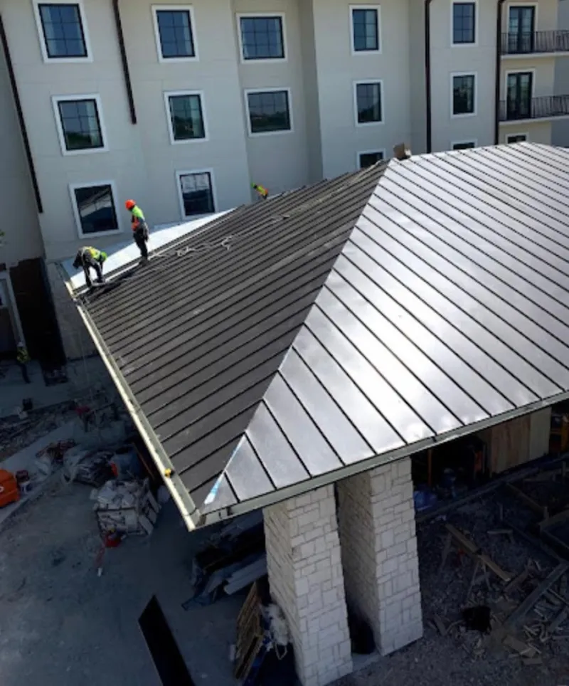 Crew installing standing seam metal roof panels on a commercial project in Richmond Heights